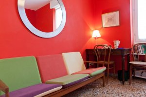Nella camera rossa è disponibile tavolino da lavoro/studio/colazione con sedie, un divano, armadio guardaroba, comodini con luce da lettura e un bello specchio di design.